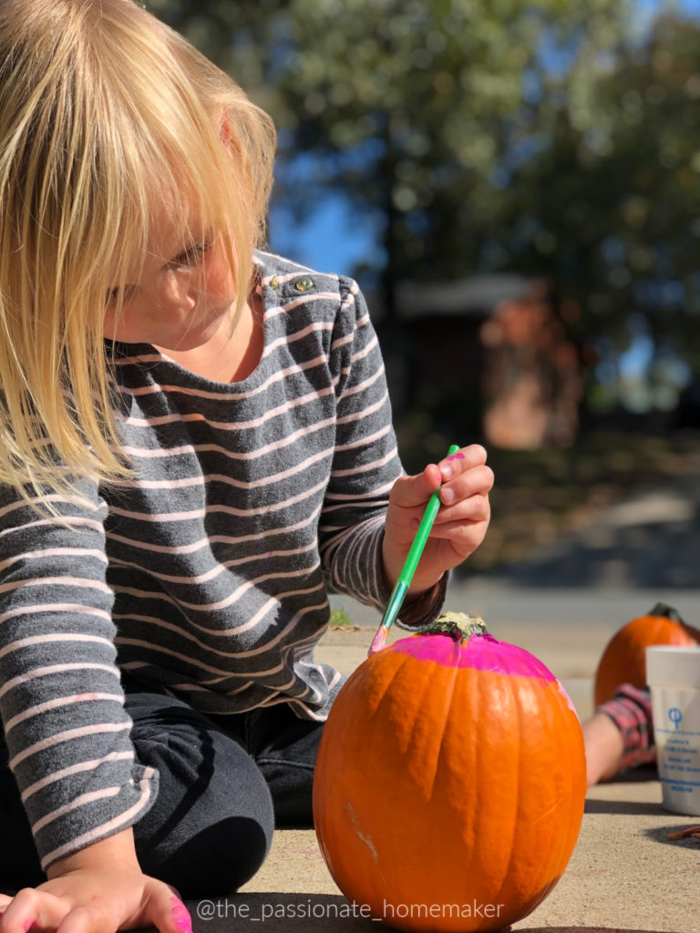 Young girl painting a pumpkin
